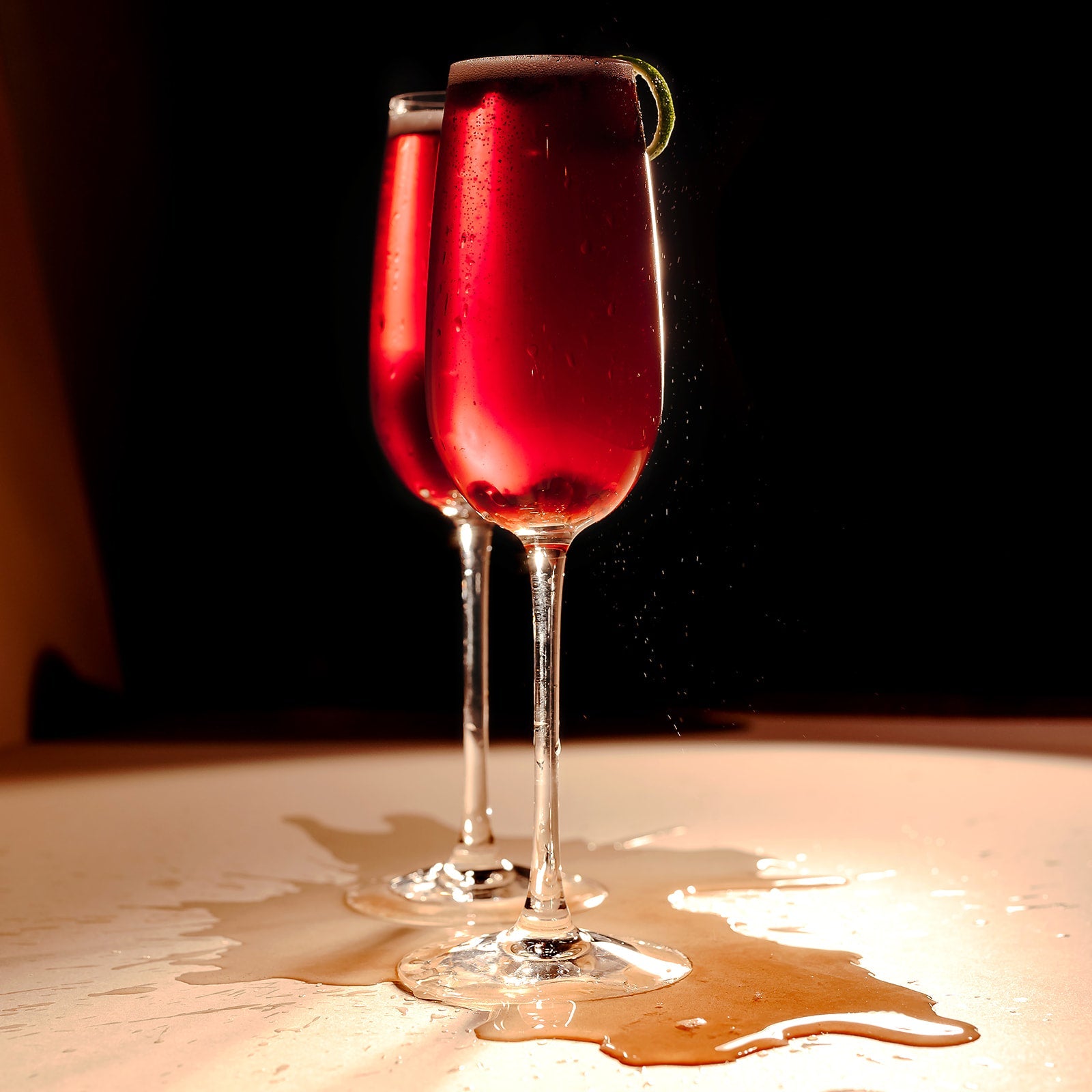 Nine Tines Pomegranate 75 cocktail in champagne flute with pomegranate seeds and lime twist