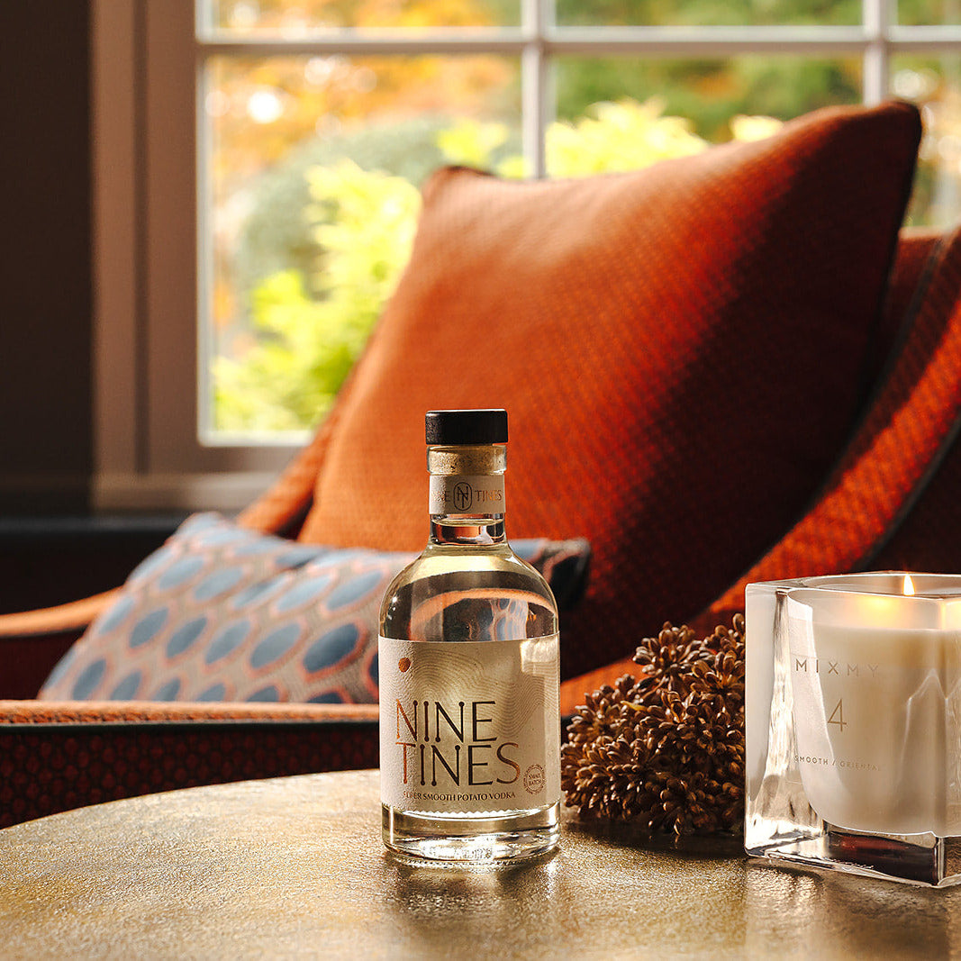 Nine Tines 20cl bottle and candle on a table with a cozy indoor setting